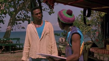 Movie still from “Cool Runnings” (1993), directed by Jon Turteltaub – A man and a woman standing next to each other on the beach; Medium shot, Over the shoulder angle