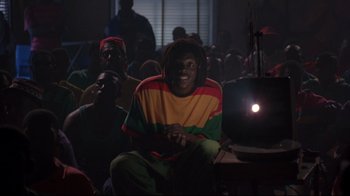 Movie still from “Cool Runnings” (1993), directed by Jon Turteltaub – A group of people sitting in front of a projector screen; Medium shot, Low angle