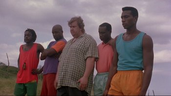 Movie still from “Cool Runnings” (1993), directed by Jon Turteltaub – A group of men standing next to each other in a field; Medium shot, Low angle