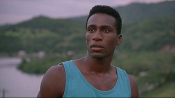 Movie still from “Cool Runnings” (1993), directed by Jon Turteltaub – A man in a blue shirt is looking into the distance; Close Up shot, Low angle
