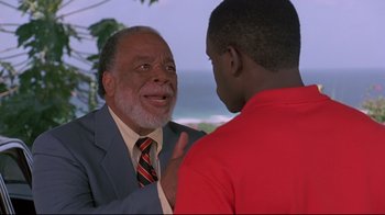 Movie still from “Cool Runnings” (1993), directed by Jon Turteltaub – A man in a business suit talking to another man in a red shirt; Close Up shot, Over the shoulder angle