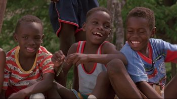 Movie still from “Cool Runnings” (1993), directed by Jon Turteltaub – A group of young boys sitting next to each other on the ground; Medium shot, Low angle