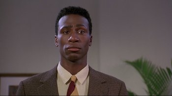 Movie still from “Cool Runnings” (1993), directed by Jon Turteltaub – A man in a suit and tie looking sad; Close Up shot, Low angle