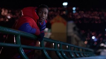 Movie still from “Cool Runnings” (1993), directed by Jon Turteltaub – A young man leaning on a railing at night; Medium shot, Low angle