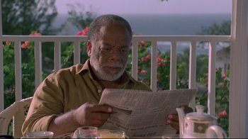 Movie still from “Cool Runnings” (1993), directed by Jon Turteltaub – An older man sitting at a table reading a newspaper; Close Up shot, Low angle