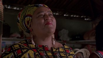 Movie still from “Cool Runnings” (1993), directed by Jon Turteltaub – An older woman wearing a head scarf and a yellow and black dress; Close Up shot, Low angle