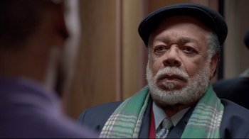 Movie still from “Cool Runnings” (1993), directed by Jon Turteltaub – An older man wearing a hat and a scarf; Close Up shot, Over the shoulder angle