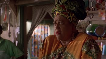 Movie still from “Cool Runnings” (1993), directed by Jon Turteltaub – An older woman wearing an orange and yellow outfit; Close Up shot, Low angle