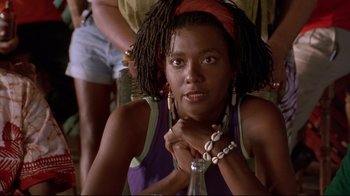 Movie still from “Cool Runnings” (1993), directed by Jon Turteltaub – A woman with dreadlocks sitting in front of other people; Close Up shot, Low angle