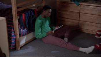 Movie still from “Cool Runnings” (1993), directed by Jon Turteltaub – A man sitting on the floor using a tablet computer; Medium shot, High angle