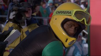 Movie still from “Cool Runnings” (1993), directed by Jon Turteltaub – A man wearing a yellow and black motorcycle helmet; Close Up shot, Low angle