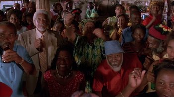 Movie still from “Cool Runnings” (1993), directed by Jon Turteltaub – A group of people gathered together in a room; Medium shot, Low angle