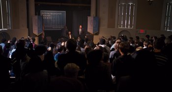 Movie still from “The Front Runner” (2018), directed by Jason Reitman – A group of people sitting in front of an audience; Extreme Wide shot, High angle