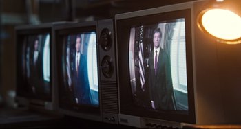 Movie still from “The Front Runner” (2018), directed by Jason Reitman – Two televison monitors with a man in a suit on them; Medium shot, High angle