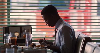 Movie still from “The Front Runner” (2018), directed by Jason Reitman – A man sitting at a table with a plate of food in front of him; Medium shot, Over the shoulder angle