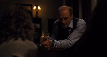 Movie still from “The Front Runner” (2018), directed by Jason Reitman – An older man sitting at a table with a bottle of beer; Medium shot, Over the shoulder angle