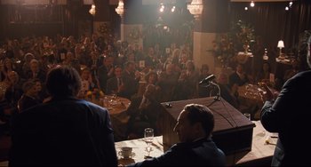 Movie still from “The Front Runner” (2018), directed by Jason Reitman – A group of people sitting at tables with microphones and microphones; Wide shot, High angle