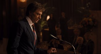 Movie still from “The Front Runner” (2018), directed by Jason Reitman – A man standing at a podium speaking into a microphone; Medium shot, Over the shoulder angle