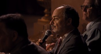 Movie still from “The Front Runner” (2018), directed by Jason Reitman – A man in a suit and tie holding a microphone; Close Up shot, Over the shoulder angle