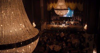 Movie still from “The Front Runner” (2018), directed by Jason Reitman – A group of people sitting at tables in front of a large chandelier; Extreme Wide shot, High angle