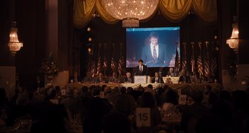 Movie still from “The Front Runner” (2018), directed by Jason Reitman – A man in a suit is giving a speech to a group of people; Wide shot, Over the shoulder angle