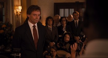 Movie still from “The Front Runner” (2018), directed by Jason Reitman – A man in a suit and tie standing in front of a group of people; Medium shot, Over the shoulder angle