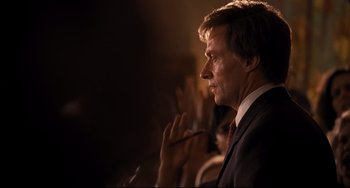 Movie still from “The Front Runner” (2018), directed by Jason Reitman – A man in a suit and red neck tie is clapping his hands; Close Up shot, Over the shoulder angle