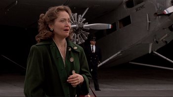 Movie still from “Cool World” (1992), directed by Ralph Bakshi – A woman in a green coat standing in front of an airplane; Medium shot, Low angle