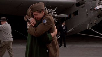 Movie still from “Cool World” (1992), directed by Ralph Bakshi – A couple of people that are hugging in front of an airplane; Medium shot, Low angle