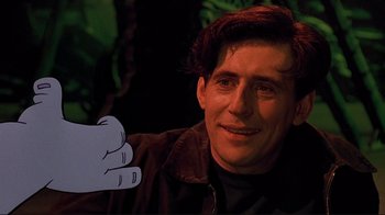 Movie still from “Cool World” (1992), directed by Ralph Bakshi – A man holding a fake hand up to his face; Close Up shot, Over the shoulder angle