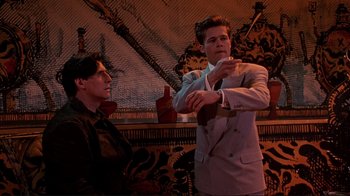 Movie still from “Cool World” (1992), directed by Ralph Bakshi – A man in a suit and tie standing next to another man in a suit and tie; Medium shot, Low angle