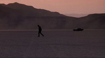 Movie still from “Cool World” (1992), directed by Ralph Bakshi – A man walking in the desert with a car in the background; Extreme Wide shot, Low angle
