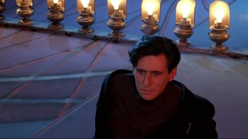 Movie still from “Cool World” (1992), directed by Ralph Bakshi – A man sitting in front of a row of oil lamps; Medium shot, Low angle