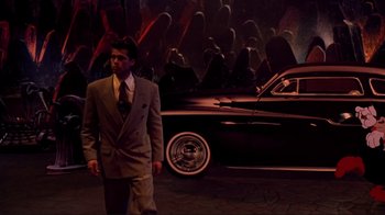 Movie still from “Cool World” (1992), directed by Ralph Bakshi – A man standing in front of a car in a suit; Wide shot, High angle