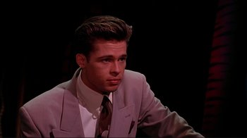 Movie still from “Cool World” (1992), directed by Ralph Bakshi – A man in a suit and tie sitting in a dark room; Close Up shot, Over the shoulder angle