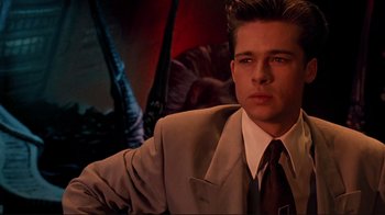 Movie still from “Cool World” (1992), directed by Ralph Bakshi – A man wearing a suit and tie sitting down; Close Up shot, High angle