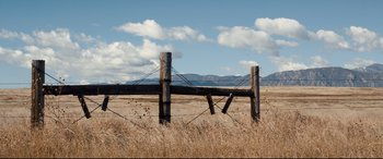 Movie still from “Cop Car” (2015), directed by Jon Watts – An old wooden fence in the middle of a dry grass field; Extreme Wide shot, Low angle