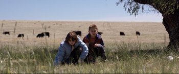 Movie still from “Cop Car” (2015), directed by Jon Watts – Two young children are sitting in the grass; Wide shot, High angle