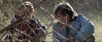 Movie still from “Cop Car” (2015), directed by Jon Watts – Two young children are playing in the brush; Close Up shot, Low angle