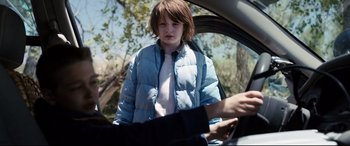 Movie still from “Cop Car” (2015), directed by Jon Watts – A young boy is sitting in the drivers seat of a car; Medium shot, Over the shoulder angle