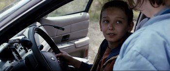 Movie still from “Cop Car” (2015), directed by Jon Watts – A boy sitting in the driver's seat of a car; Close Up shot, Over the shoulder angle