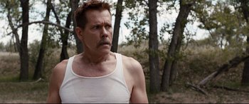 Movie still from “Cop Car” (2015), directed by Jon Watts – A person wearing a tank top near a forest; Close Up shot, Over the shoulder angle