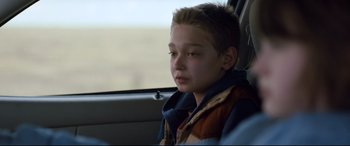 Movie still from “Cop Car” (2015), directed by Jon Watts – A boy sitting in the back seat of a car looking out the window; Close Up shot, Over the shoulder angle