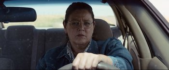 Movie still from “Cop Car” (2015), directed by Jon Watts – An older woman wearing glasses driving in a car; Close Up shot, Over the shoulder angle