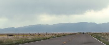 Movie still from “Cop Car” (2015), directed by Jon Watts – A road that has some grass on it; Extreme Wide shot, Low angle