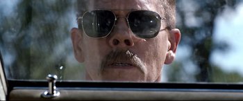Movie still from “Cop Car” (2015), directed by Jon Watts – A person wearing a pair of sunglasses; Close Up shot, Low angle