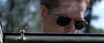 Movie still from “Cop Car” (2015), directed by Jon Watts – A person wearing a pair of sunglasses; Close Up shot, Over the shoulder angle