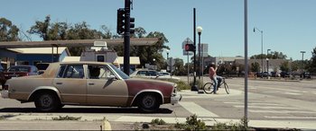 Movie still from “Cop Car” (2015), directed by Jon Watts – An old car is parked on the side of the road; Wide shot, Over the shoulder angle