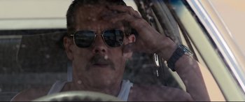Movie still from “Cop Car” (2015), directed by Jon Watts – A man with a mustache wearing sunglasses while sitting in a car; Close Up shot, Low angle