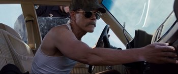 Movie still from “Cop Car” (2015), directed by Jon Watts – A man in a hat and sunglasses driving a car; Close Up shot, Over the shoulder angle